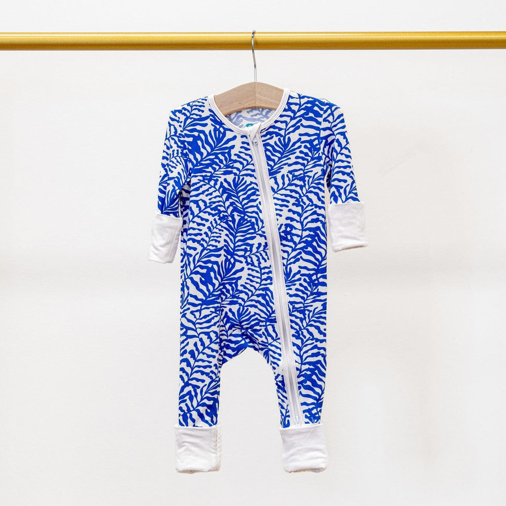 Seabreeze blue and white footie pajama with a fern-like pattern, featuring a two-way zipper and white trim and cuffs, hanging on a wooden hanger from a gold-colored rod against a plain white background.