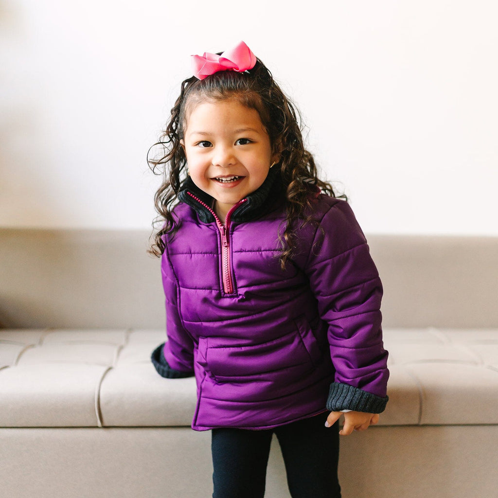 The Jam/Maroon
Little girl with curly brown hair and a pink bow is wearing a purple car seat coat.  Her coat is zipped up and she is smiling at the camera.