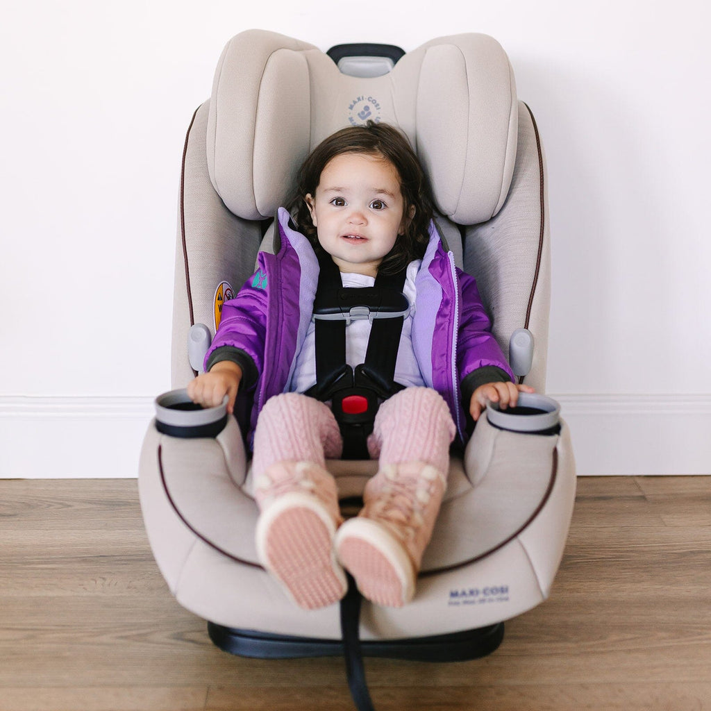 Sparkalot/Purple
Baby girl with brown hair is wearing a purple car seat coat.  The girl is sitting in a tan carseat.  The car seat coat is open showing the buckled harness.  The girl is looking at the camera, 