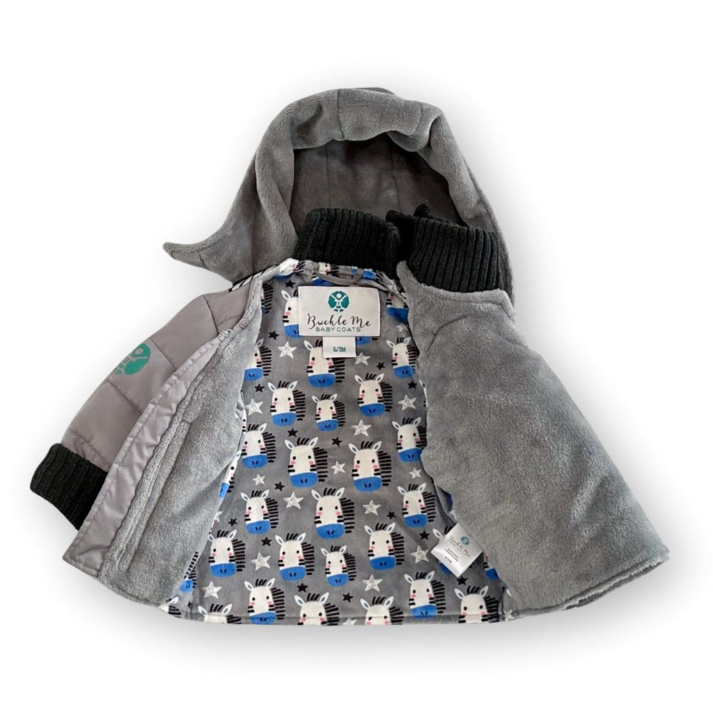 Sub-Zebro/Grey
Grey hooded car seat coat with charcoal grey cuffs is displayed on a white background.  The coat has a grey and zebra print sherpa interior. The coat is unzipped.