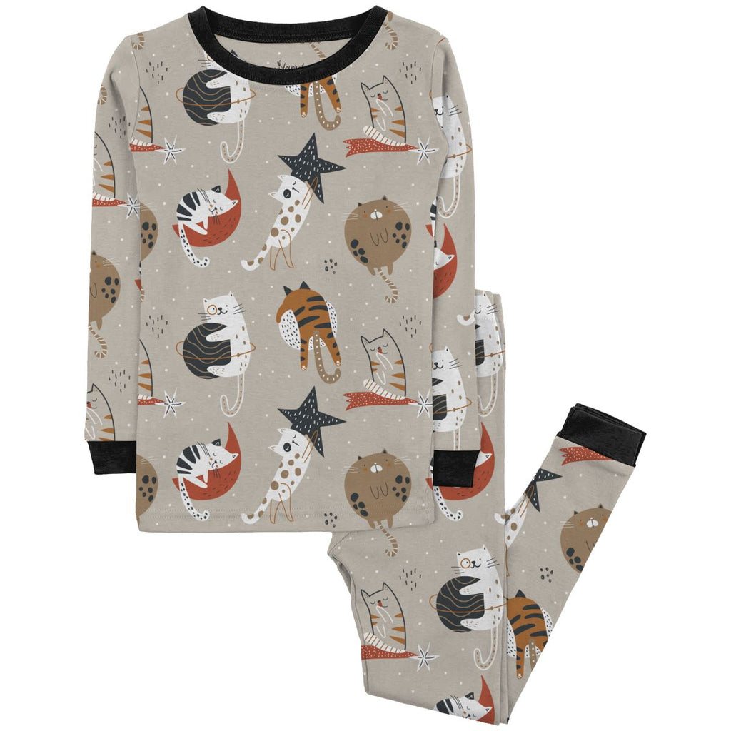 Cool Cat Jams Big Kids a light brown pajama set featuring a whimsical cat pattern with various playful poses and expressions. The pajama top has long sleeves and is paired with matching pants. The cats are illustrated in shades of black, white, orange, and brown, surrounded by abstract star and moon shapes in white and red. The set has black trim on the collar and cuffs. The pajama is displayed on a plain white background.